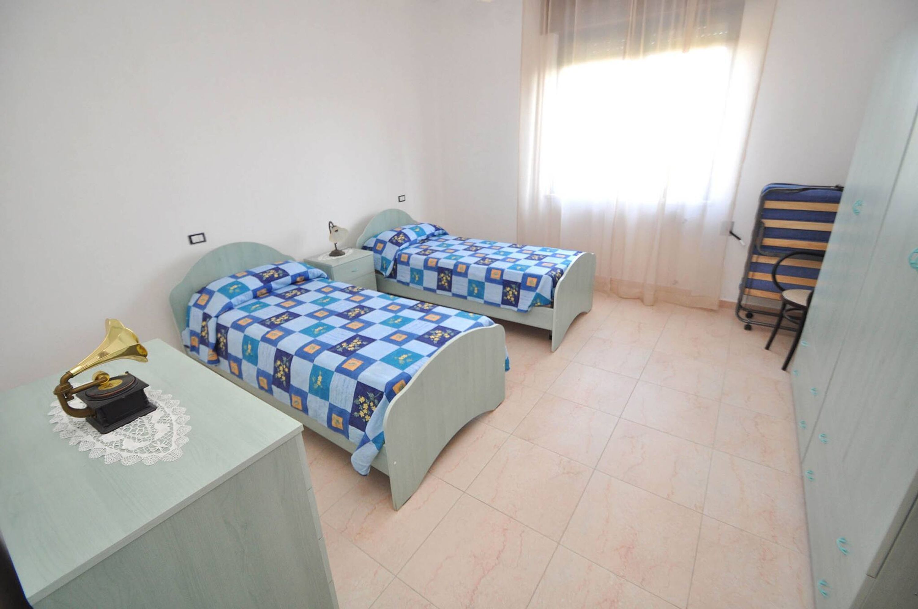 A room with two beds, a desk with a lamp, and a chair.