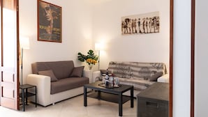 A living room with a sofa, a coffee table, a lamp, and a poster on the wall.