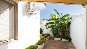 A small patio area with a white wall, a table, a chair, and potted plants. - Villetta DEI Gigli in Marina di Mancaversa (Taviano)