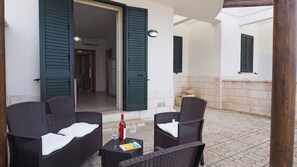 A patio area with wicker furniture and a wine bottle. - Villetta Garden Verardi (Racale)