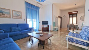 A living room with a blue sofa, a wooden coffee table, and a television on a stand. - Villa Fede - 3 Bedrooms 2 Bathrooms air Conditioning by the sea (Taviano)