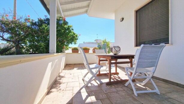 A balcony with a table and two chairs, potted plants, and a view of the surrounding area. - Villa Fede - 3 Bedrooms 2 Bathrooms air Conditioning by the sea (Taviano)