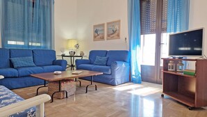 A living room with two blue sofas, a wooden coffee table, a TV on a wooden stand, and a small table with decorative items. - Villa Fede - 3 Bedrooms 2 Bathrooms air Conditioning by the sea (Taviano)