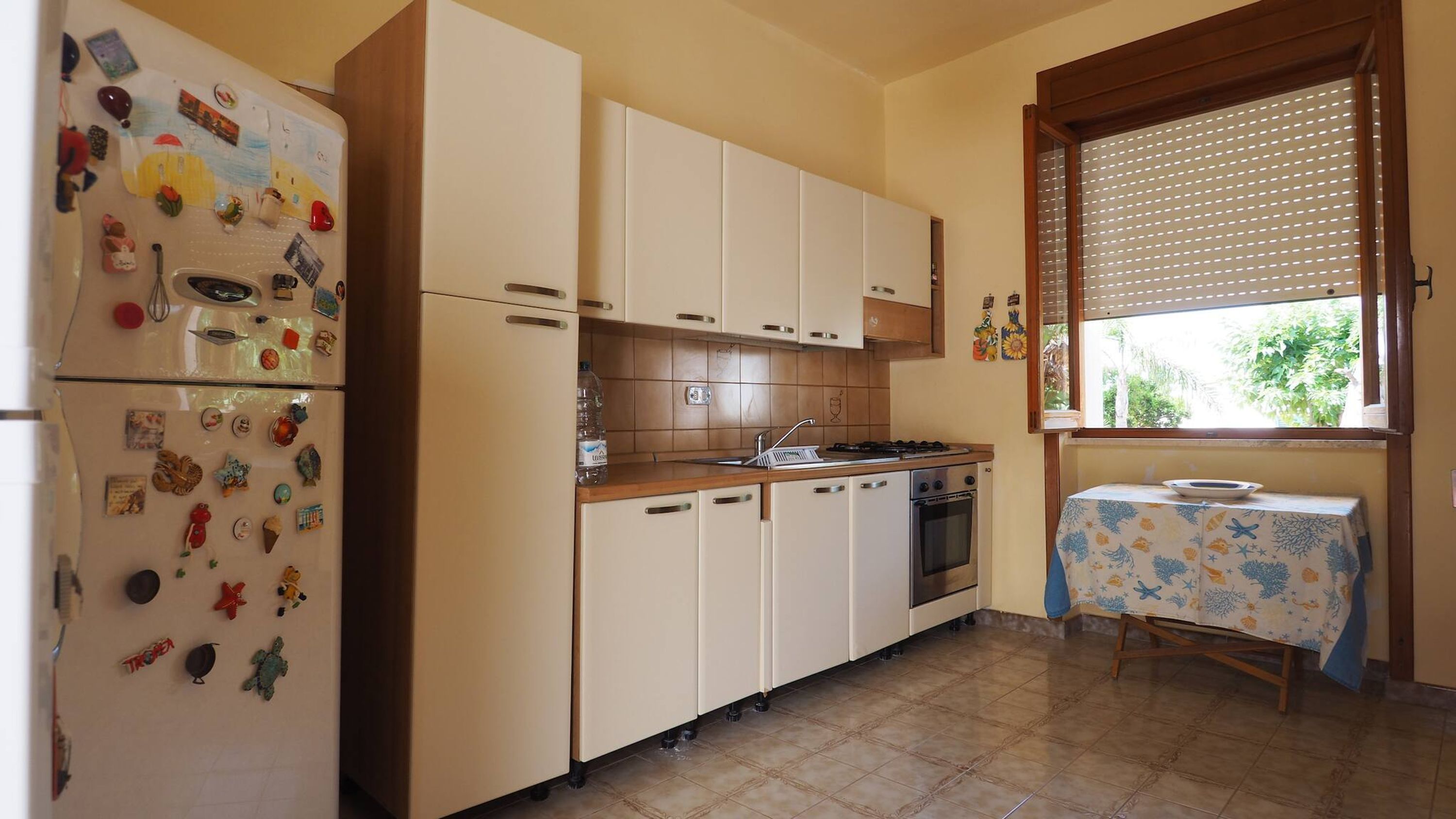 A compact kitchen with a refrigerator, stove, sink, and cabinets.