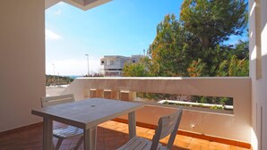 A balcony with a table and chairs, overlooking a residential area with trees and buildings. - Villetta Baia Verde 2 (Gallipoli)