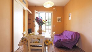 A dining area with a table set for two, a purple sofa, and a vase of flowers. - Villetta Baia Verde 2 (Gallipoli)