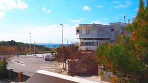 Un bâtiment situé sur la côte, offrant une vue sur la mer, avec un espace de stationnement et un passage piéton.