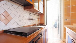 A kitchen with a gas stove, a sink, and a window with a view of the outside. - Villetta Baia Verde 2 (Gallipoli)