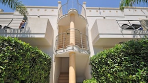 Ein modernes Gebäude mit einer zentralen Treppe, umgeben von Grünflächen.
