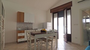 A compact kitchen with white cabinets, a wooden countertop, and a dining area with a table and chairs.
