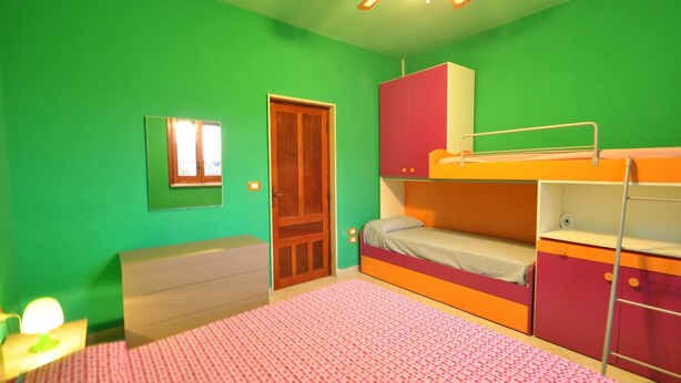 A room with green walls, a bunk bed, a wooden door, a small table with a lamp, and a window. - Villa for 6 People 2 Bedrooms a few Meters From the sea (Ugento)