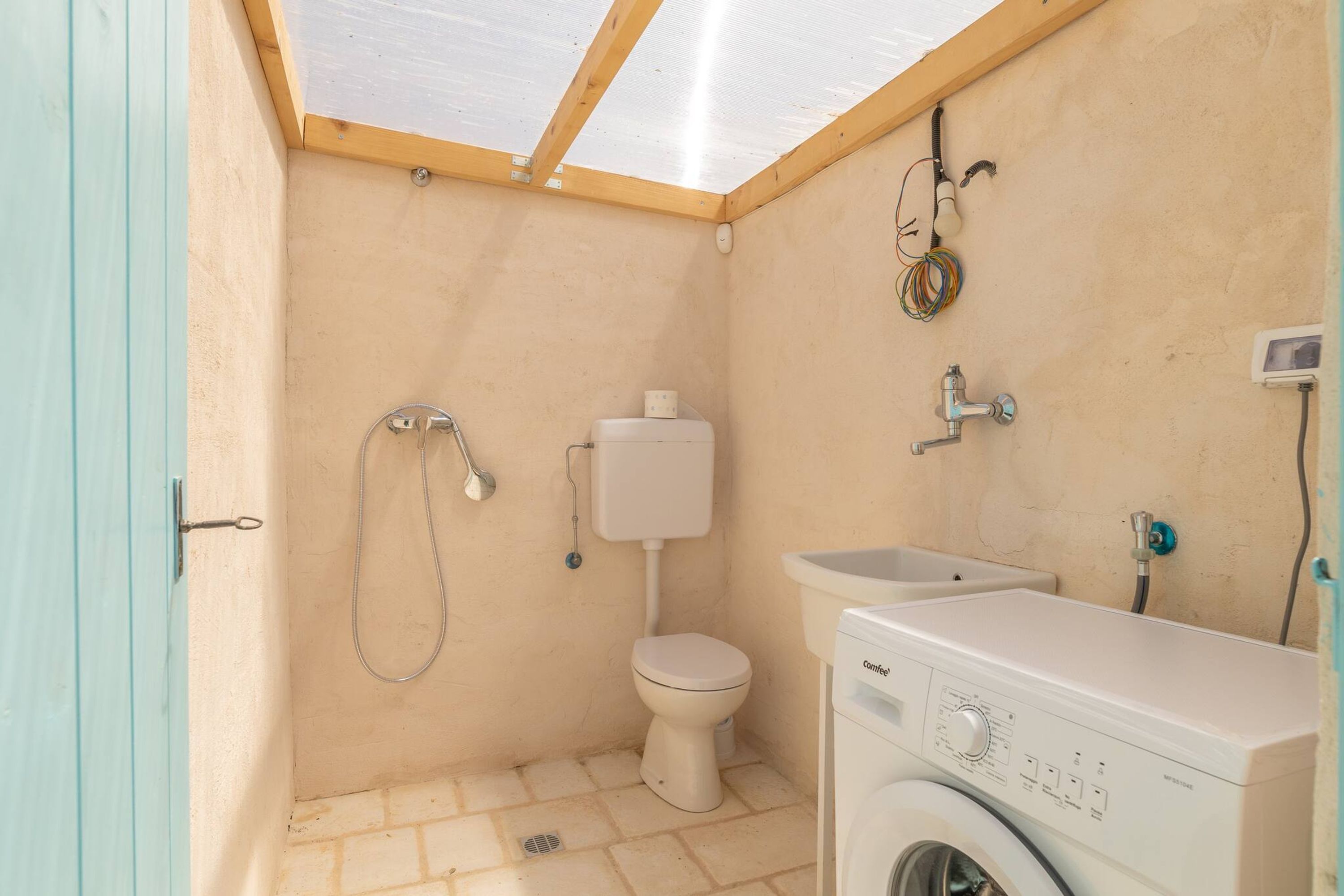 A compact bathroom with a toilet, shower, and washing machine.