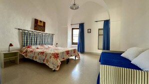 A bedroom with a bed, a bedside table, a lamp, a window with curtains, and a hanging light fixture. - App al Castello 2 by Salentoaffitti (Alliste)