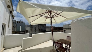 A rooftop terrace with a white umbrella, wooden table, and chairs. - App al Castello 2 by Salentoaffitti (Alliste)