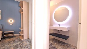 A modern bathroom with a vanity, a round mirror with underglow lighting, and a marble floor. - Suite Fontanelle Luxury 10 (Ugento)