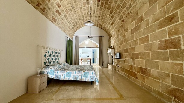 A bedroom with a bed, a nightstand, a dresser, and a view into the adjacent room. - App al Castello 1 by Salentoaffitti (Alliste)