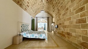 Un dormitorio con cama, mesita de noche, cómoda y vista a la habitación contigua.