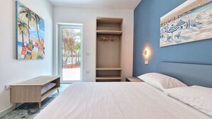 A modern bedroom with a bed, a walk-in closet, and a painting of a beach scene. - Suite Fontanelle Luxury 8 (Ugento)