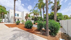 A modern building with a white exterior, surrounded by palm trees and various shrubs. - Suite Fontanelle Luxury 8 (Ugento)