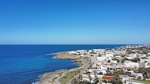A coastal town with white buildings, a clear blue sky, and a winding road along the sea. - Villetta Charme 2 in Capilungo 5 Guests by the sea (Alliste)