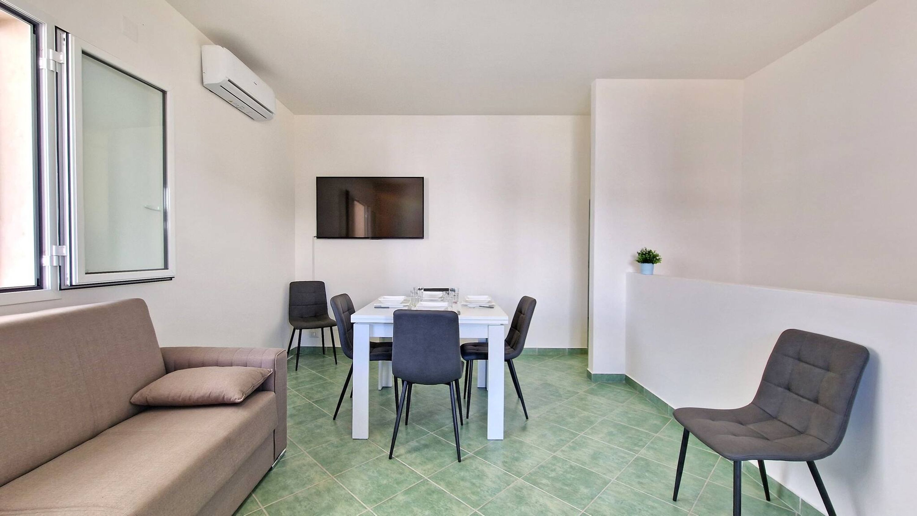 A compact living space with a dining area, a sofa, and a TV mounted on the wall.