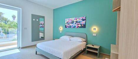 A modern bedroom with a bed, bedside tables, a mirror, and a painting.