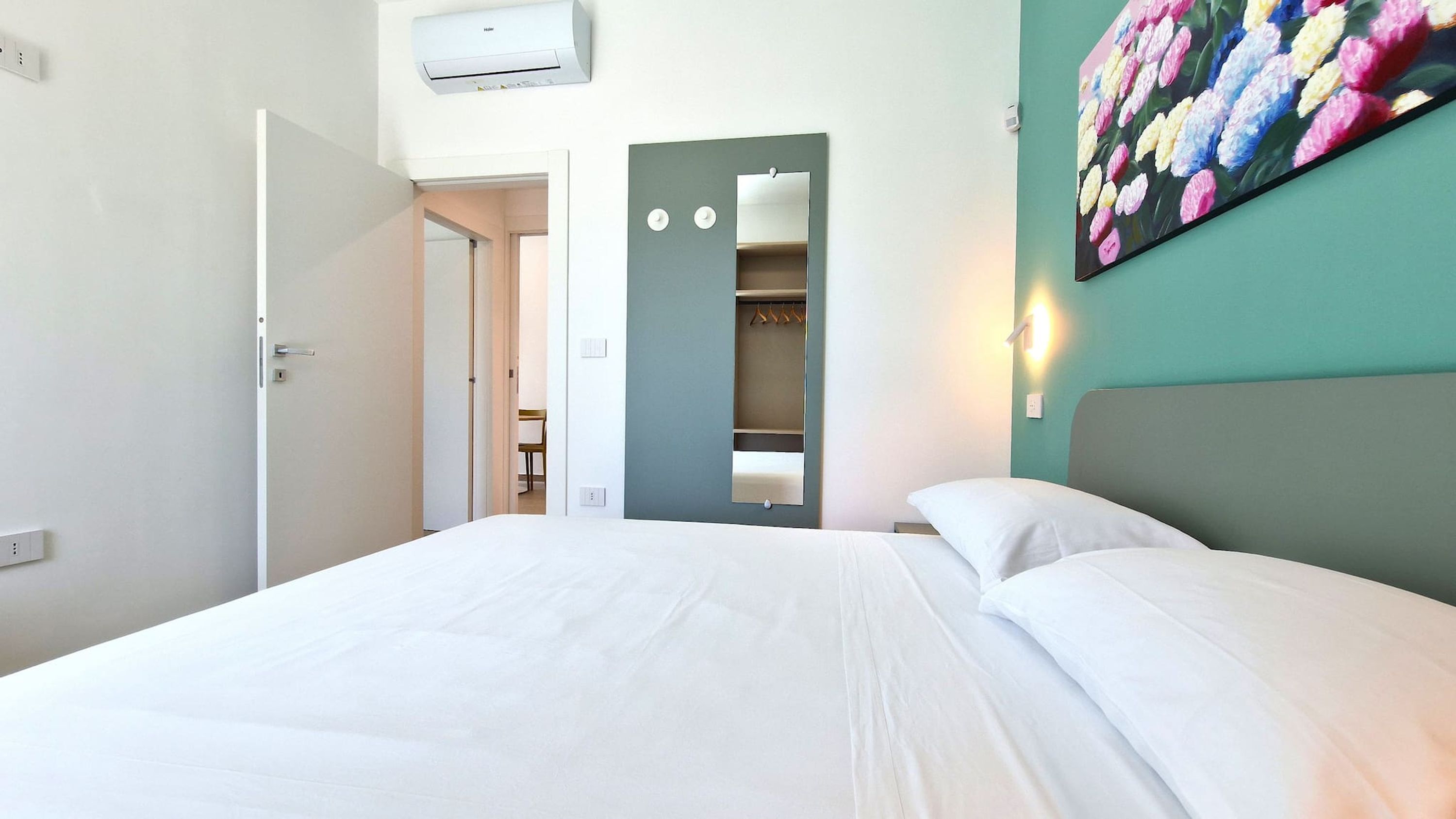 A hotel room with a bed, a wardrobe, and a mirror.