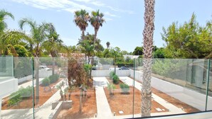 A modern outdoor area with palm trees, a glass fence, and a paved walkway. - Suite Fontanelle Luxury 6 (Ugento)