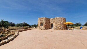 A stone building with two arched doorways and a yellow umbrella. - Trullo Meraviglia in Torre Suda (Racale)
