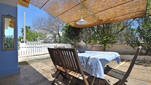 An outdoor patio with a table and chairs, a large vase, and a hanging light fixture. - Villetta Certosina 1 (Alliste)