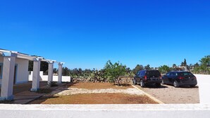 A white building with a covered patio area and two parked cars. - Villetta Certosina 1 (Alliste)