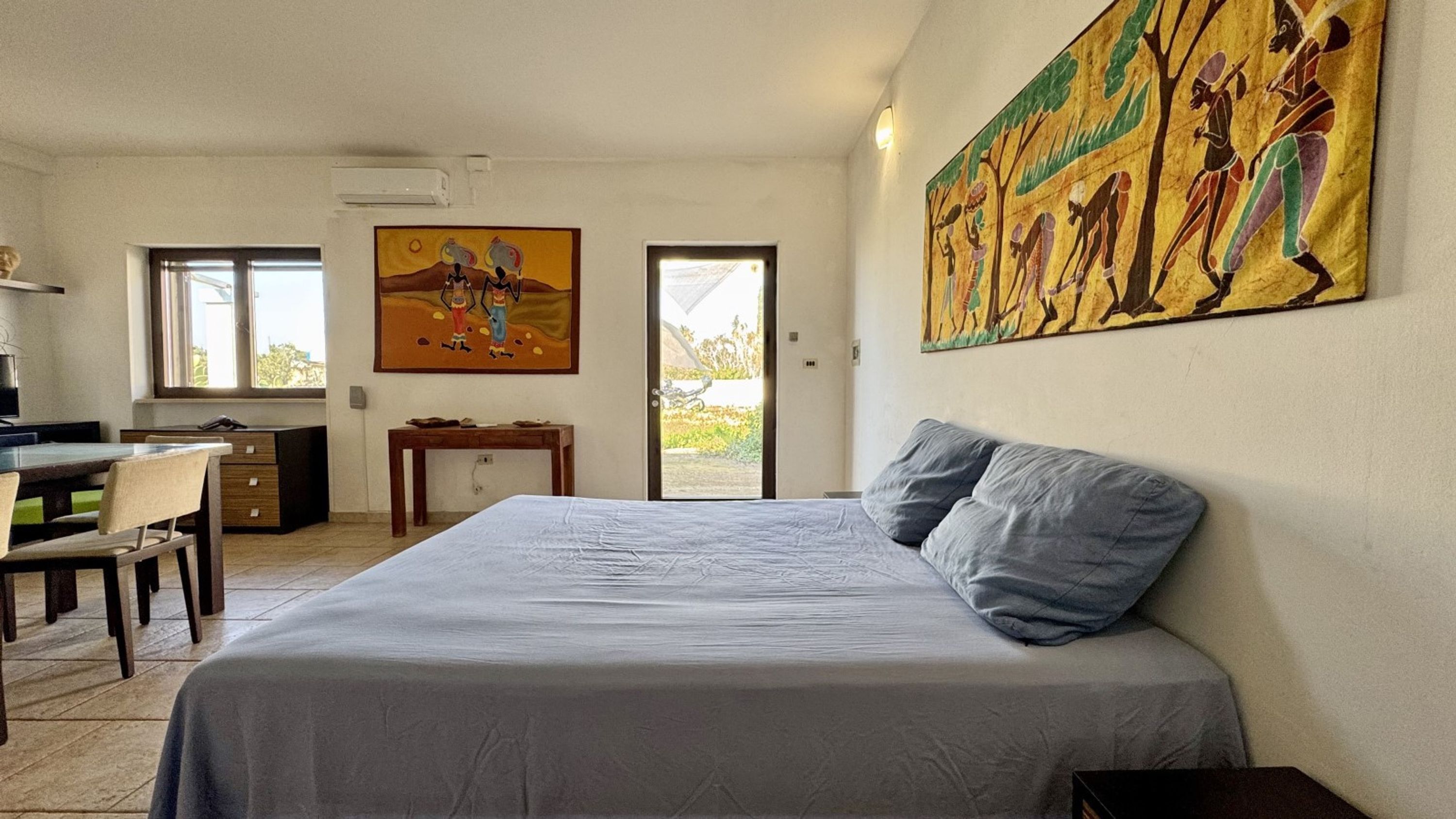 Une chambre à coucher avec un lit, un bureau et une chaise. Il y a un tableau au mur et une fenêtre.