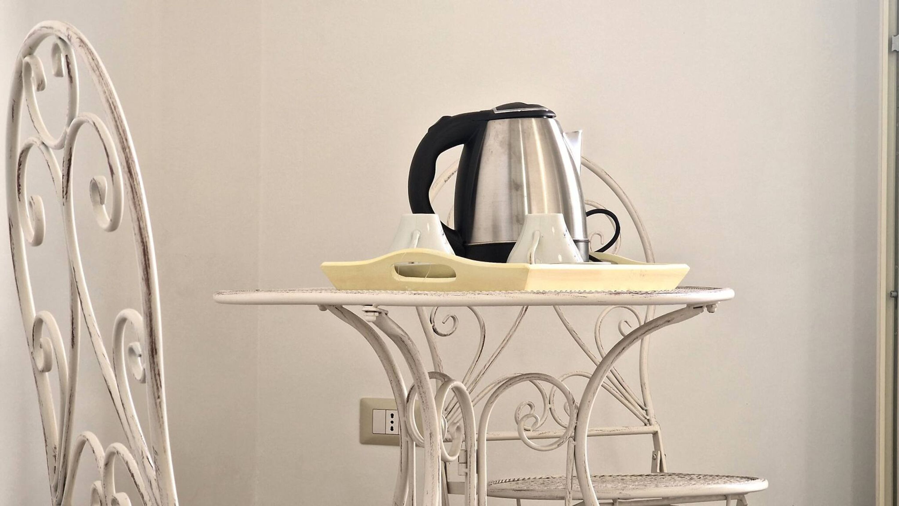 Une table en métal avec une bouilloire, des verres et un plateau.