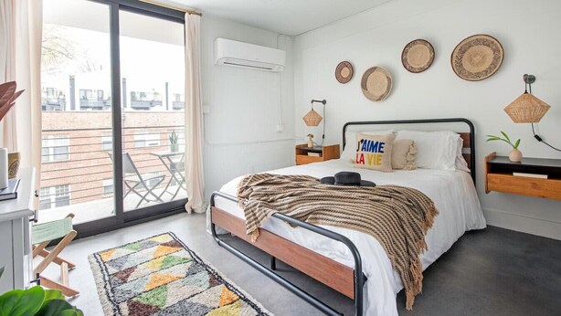 A modern bedroom with a bed, a balcony, and decorative wall plates.