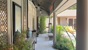 A covered walkway with decorative wall panels, hanging lanterns, and potted plants. - 3BR secluded gem w/ pool, minutes to beaches/marinas, walk to town & restaurants (Hampton Bays)