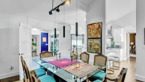 A modern dining area with a glass table, wicker chairs, and a colorful rug. - 3BR secluded gem w/ pool, minutes to beaches/marinas, walk to town & restaurants (Hampton Bays)