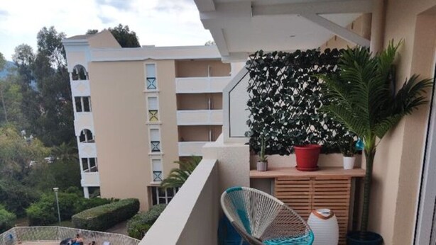 A balcony with a view of a swimming pool, a chair, and a potted plant.