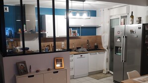 A modern kitchen with white cabinets, a stainless steel refrigerator, and a dishwasher.