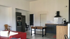 Eine moderne Wohnung mit einem roten Sofa, einem Holzesstisch, einer Küche mit schwarzem Dunstabzug und einer gefliesten Spritzschutzwand.
