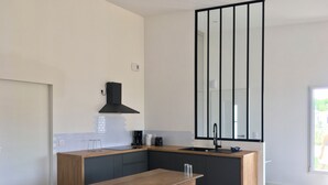 Eine moderne Küche mit einem Holztisch, dunklen Schränken und einem großen Spiegel.