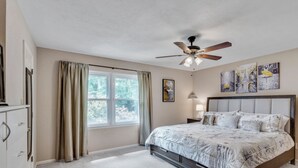 A bedroom with a bed, a ceiling fan, a window with curtains, and artwork on the wall. - Cozy 3BR townhome 5 minutes from downtown and Cascades (Tallahassee)