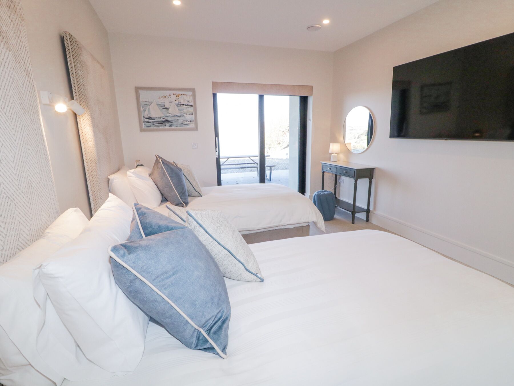 A hotel room with two beds, a large window, a flat-screen TV, and a painting on the wall.