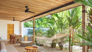Un espacio exterior moderno con techo de madera, una hamaca y plantas tropicales.