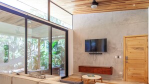 Una sala de estar moderna con un sofá, una mesa de centro y un televisor montado en la pared.