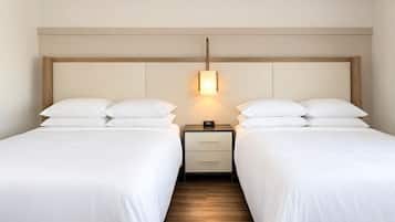 Une chambre d’hôtel avec deux lits, une table de chevet avec une lampe et un plancher en bois.
