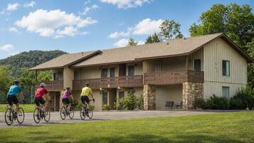 A two-story building with a balcony, stone pillars, and a paved driveway.