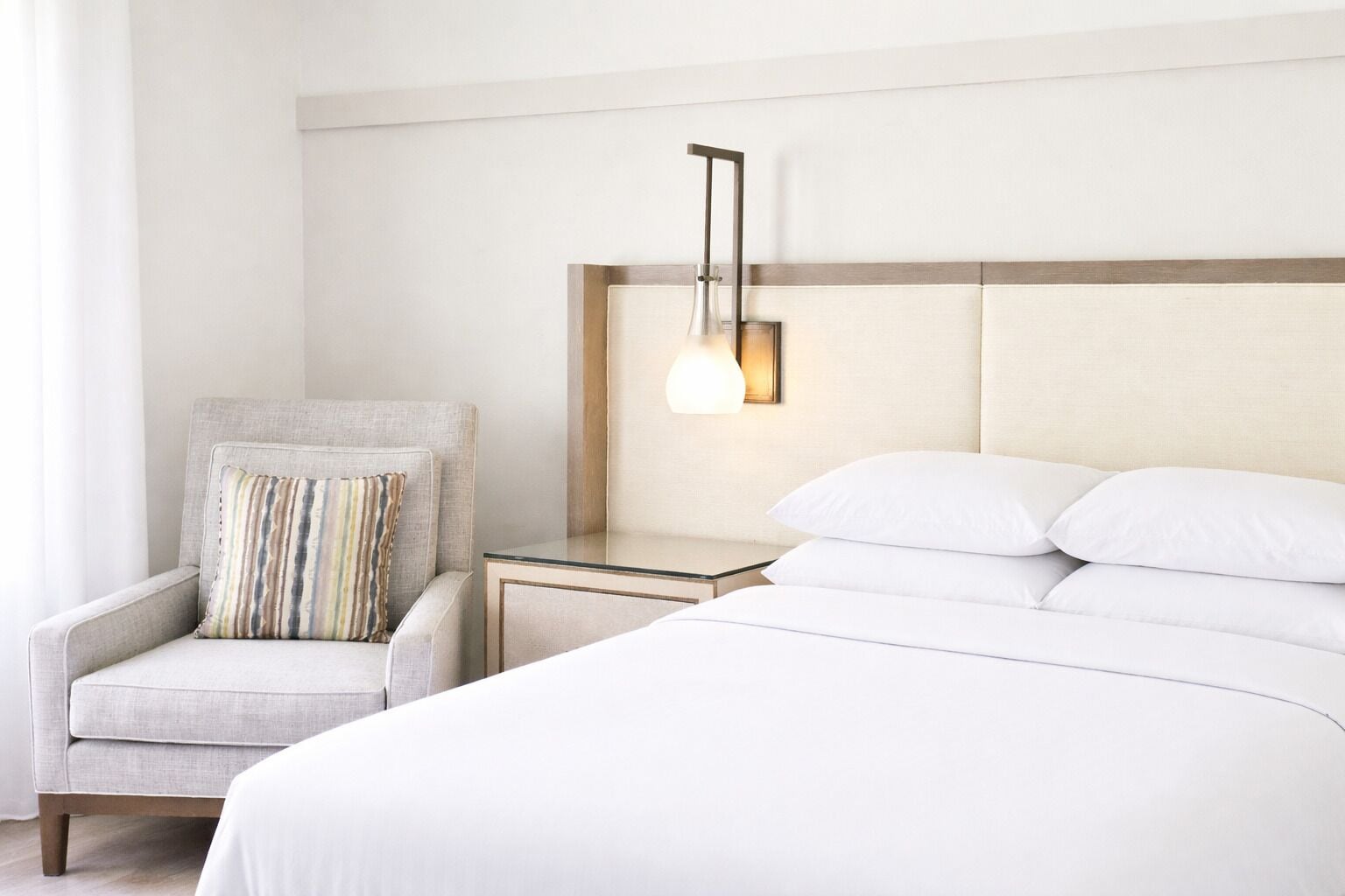 Ein Hotelzimmer mit Bett, Nachttisch, Lampe und Stuhl.