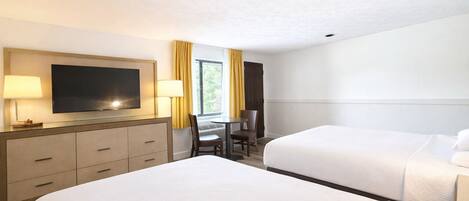 A hotel room with two beds, a desk with a chair, a TV, and a window with curtains.