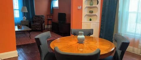 A dining area with a round table, four chairs, and a vase.