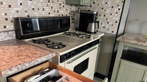 Eine Küche mit einem Gasherd, einer Kaffeemaschine und einem Schubladenorganizer für Besteck.